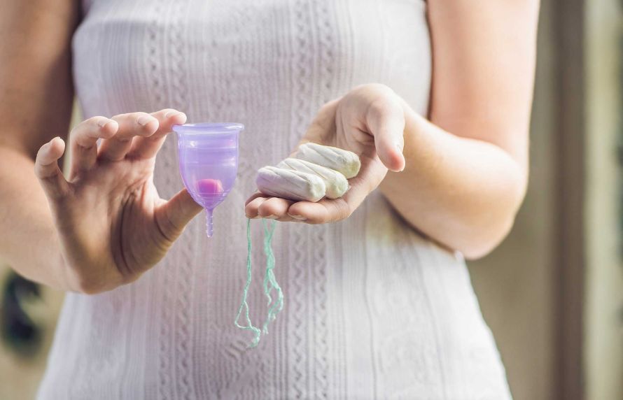 Une femmes tenant une coupe menstruelle et des tampons